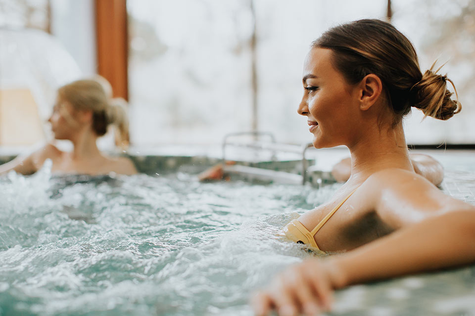 Two women in a hot tub with their arms around each other.