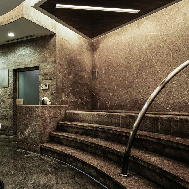 A staircase in the middle of a room with marble walls.