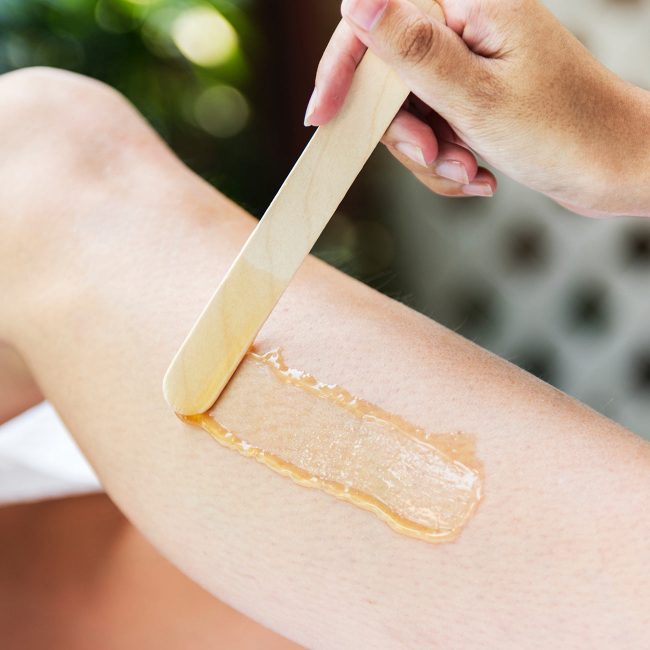 A person waxing their arm with a wooden spatula.
