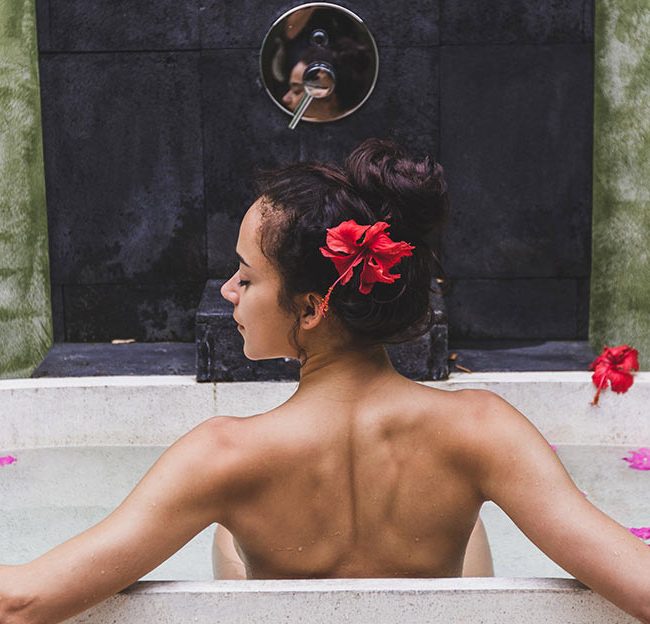 A woman sitting in the tub with her hair hanging down.