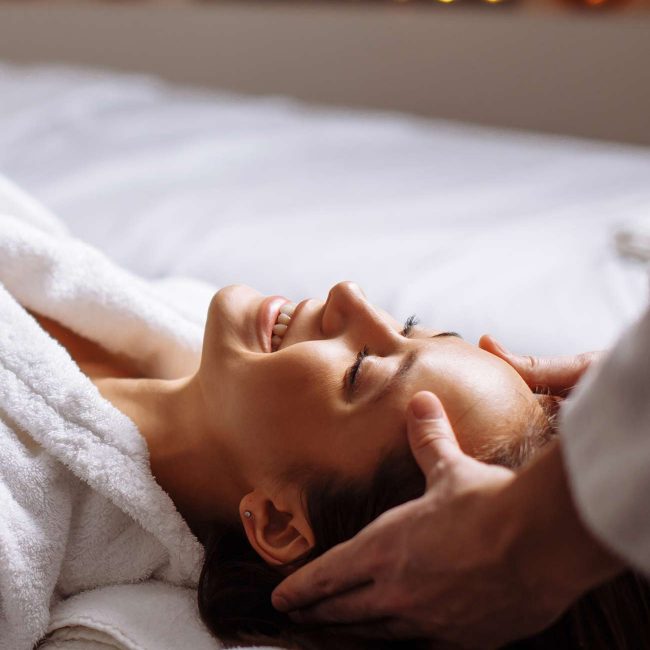 A person laying on top of a bed with their eyes closed.