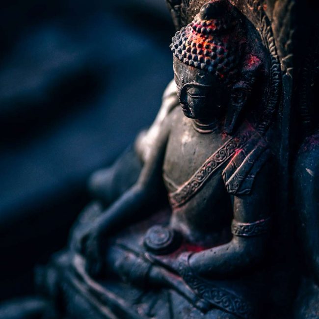 A statue of buddha sitting in the dark.