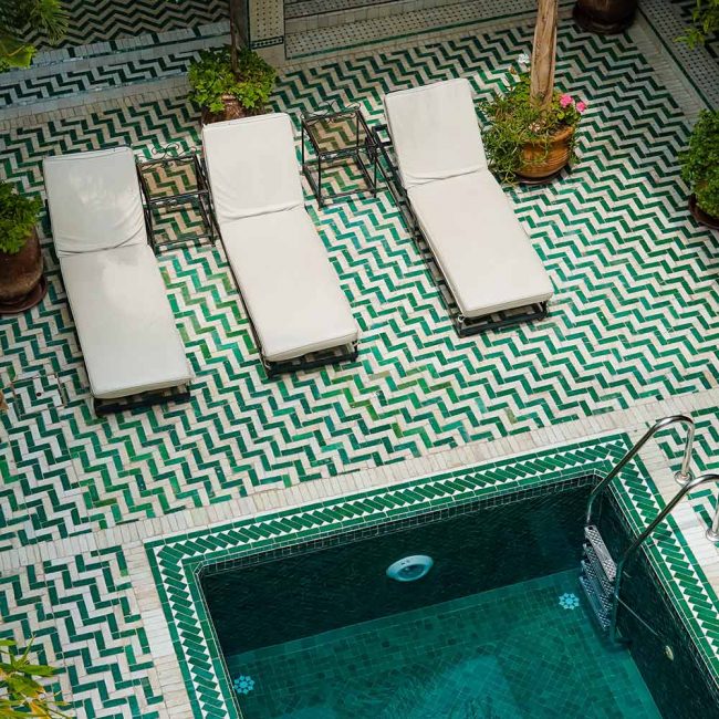 A pool with three chairs and two loungers.
