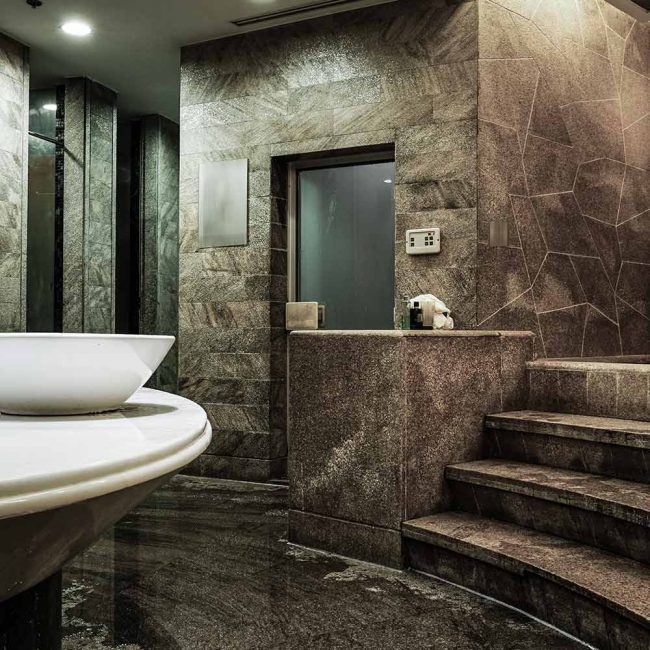 A bathroom with marble walls and floors, and a large sink.
