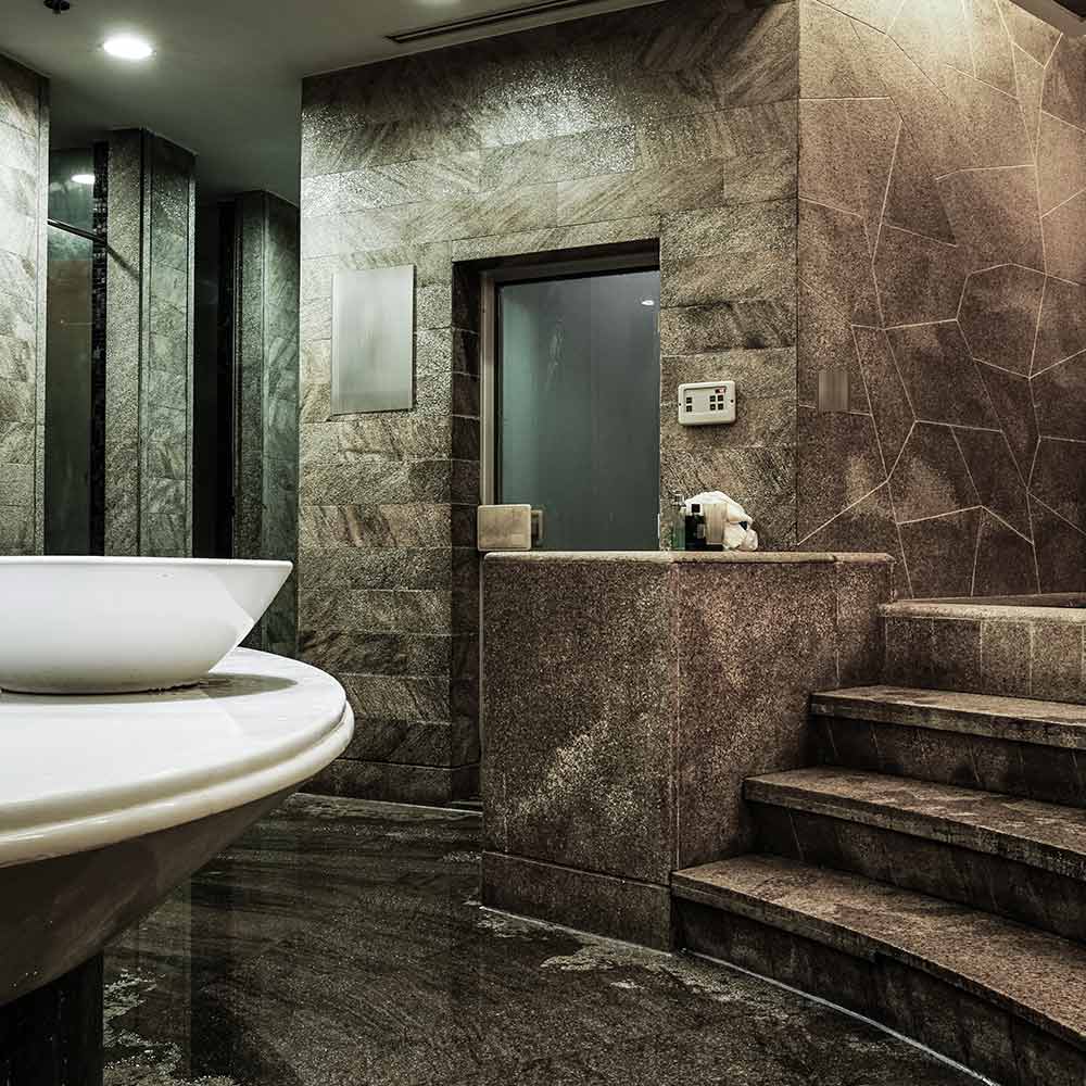 A bathroom with marble walls and floors, and a large sink.