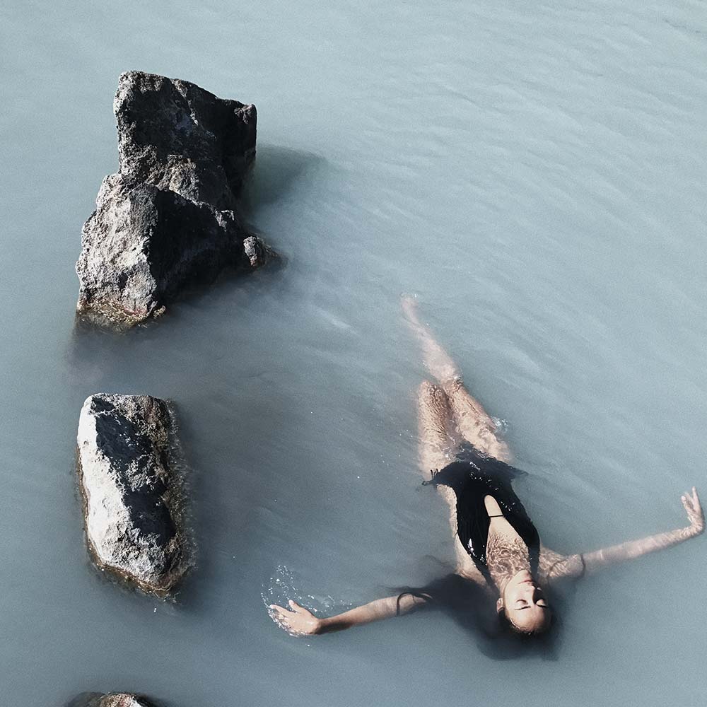 A woman in the water with rocks around her.