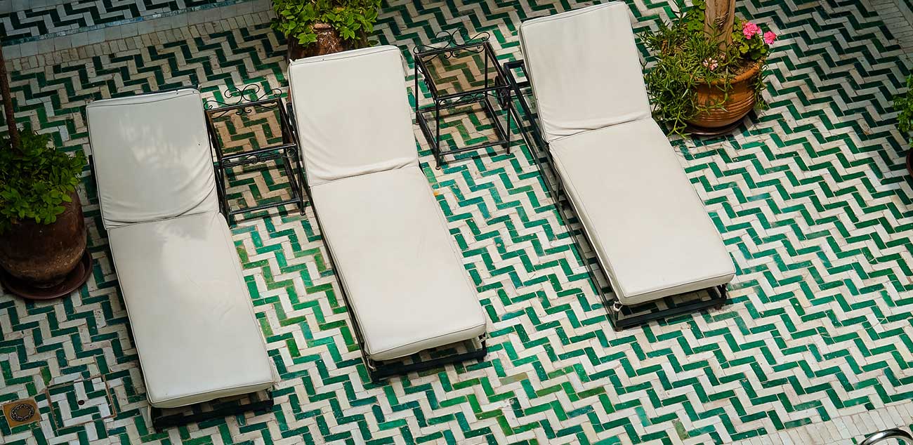 A patio with four lounge chairs and two tables.